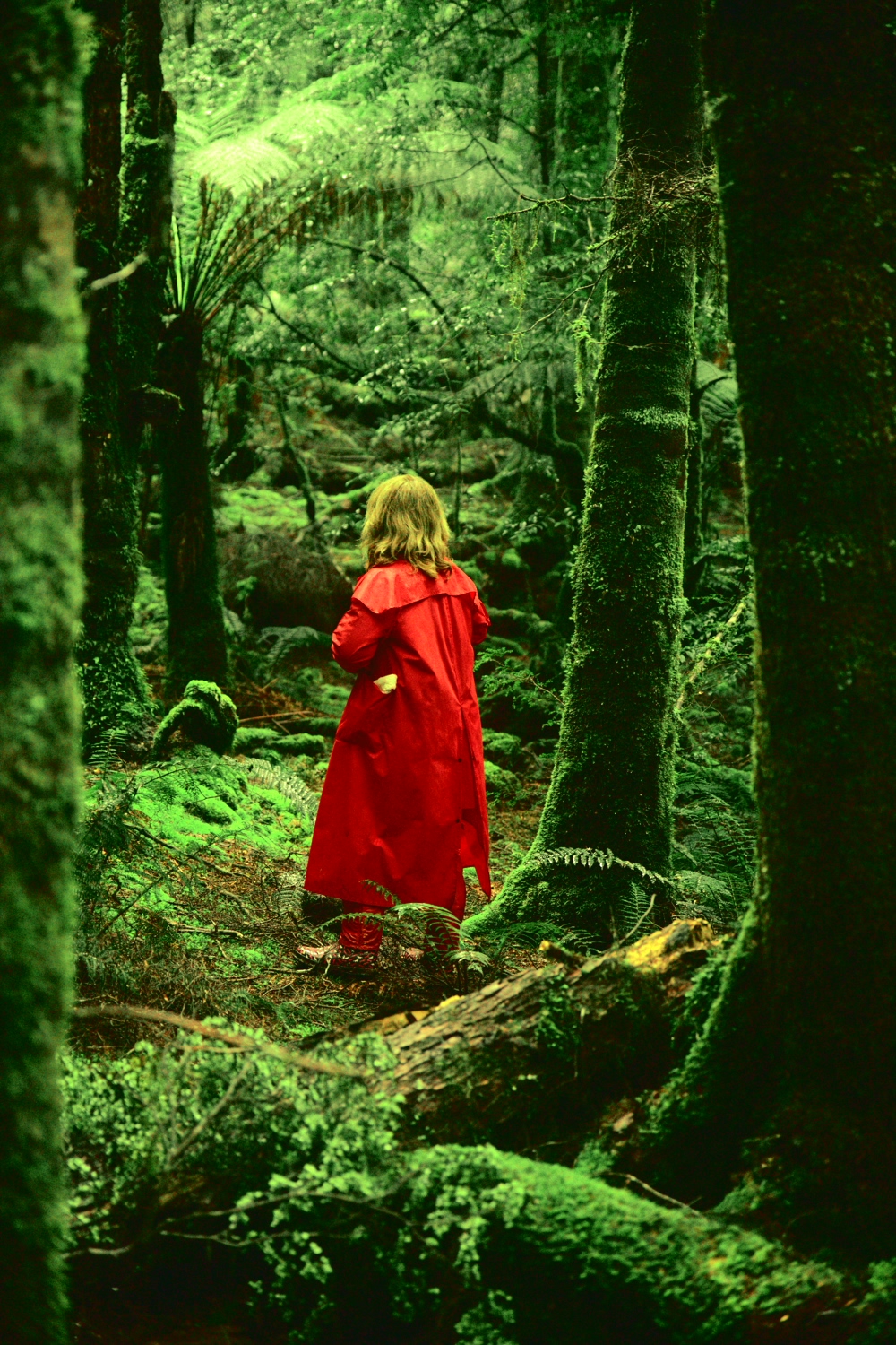 woman with red jack jacket like little red riding hood but without the hood in lush green rainforest
